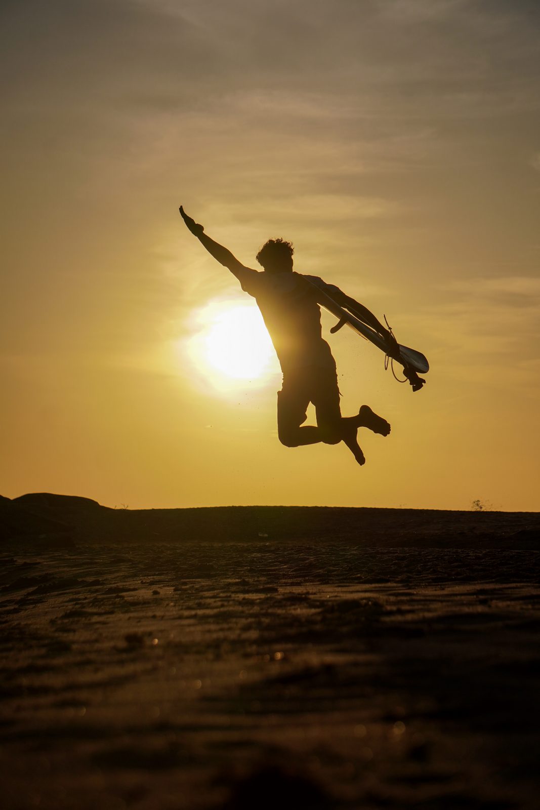 Surfer silhouetted at sunset